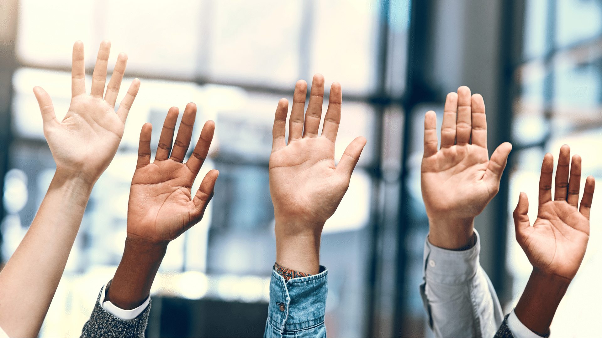 An image of a room with a bunch of people with their hands up